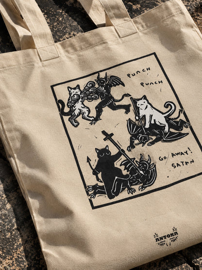 Κοντινή φωτογραφία tote bag με ασπρόμαυρο σχέδιο γάτων που πολεμούν δαίμονες
