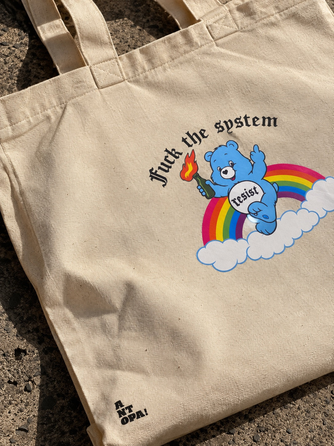Μπεζ tote bag με μπλε αρκουδάκι, ουράνιο τόξο και μήνυμα Fuck the System — Resist