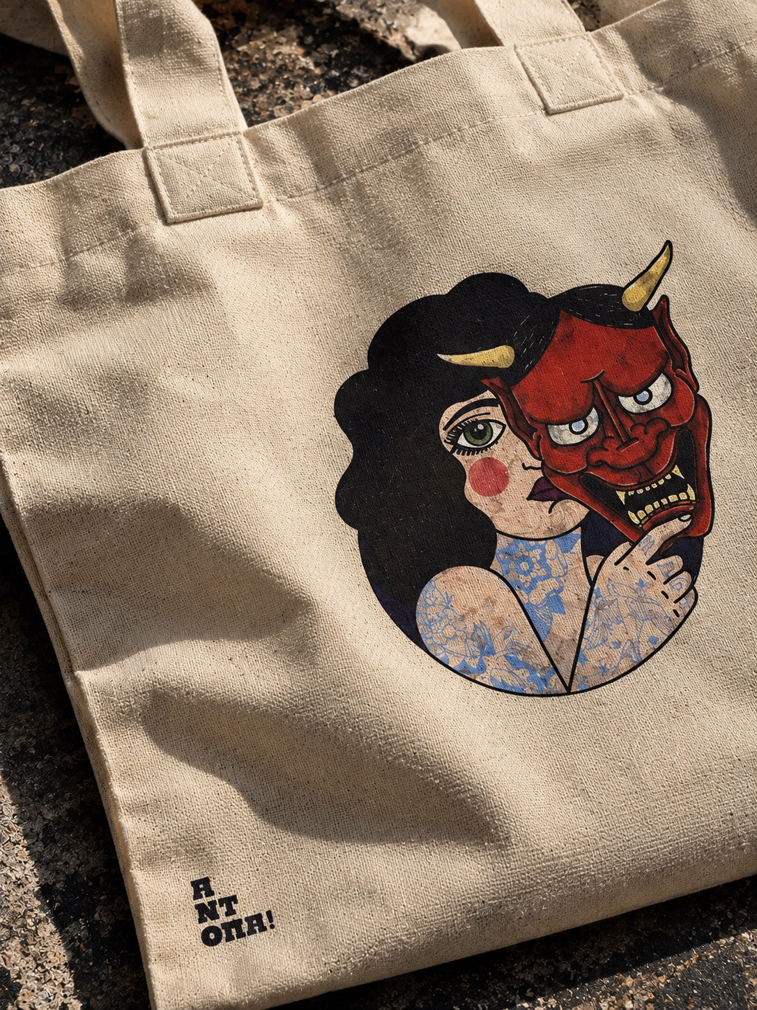 Κοντινή φωτογραφία της μπεζ tote bag με graphic γυναίκας και μάσκας Hannya