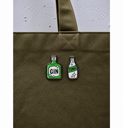 Gin and tonic wooden printed pin set displayed on olive green bag