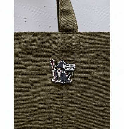 Wizard cat pin with the phrase You Shall Not Pet displayed on an olive green bag